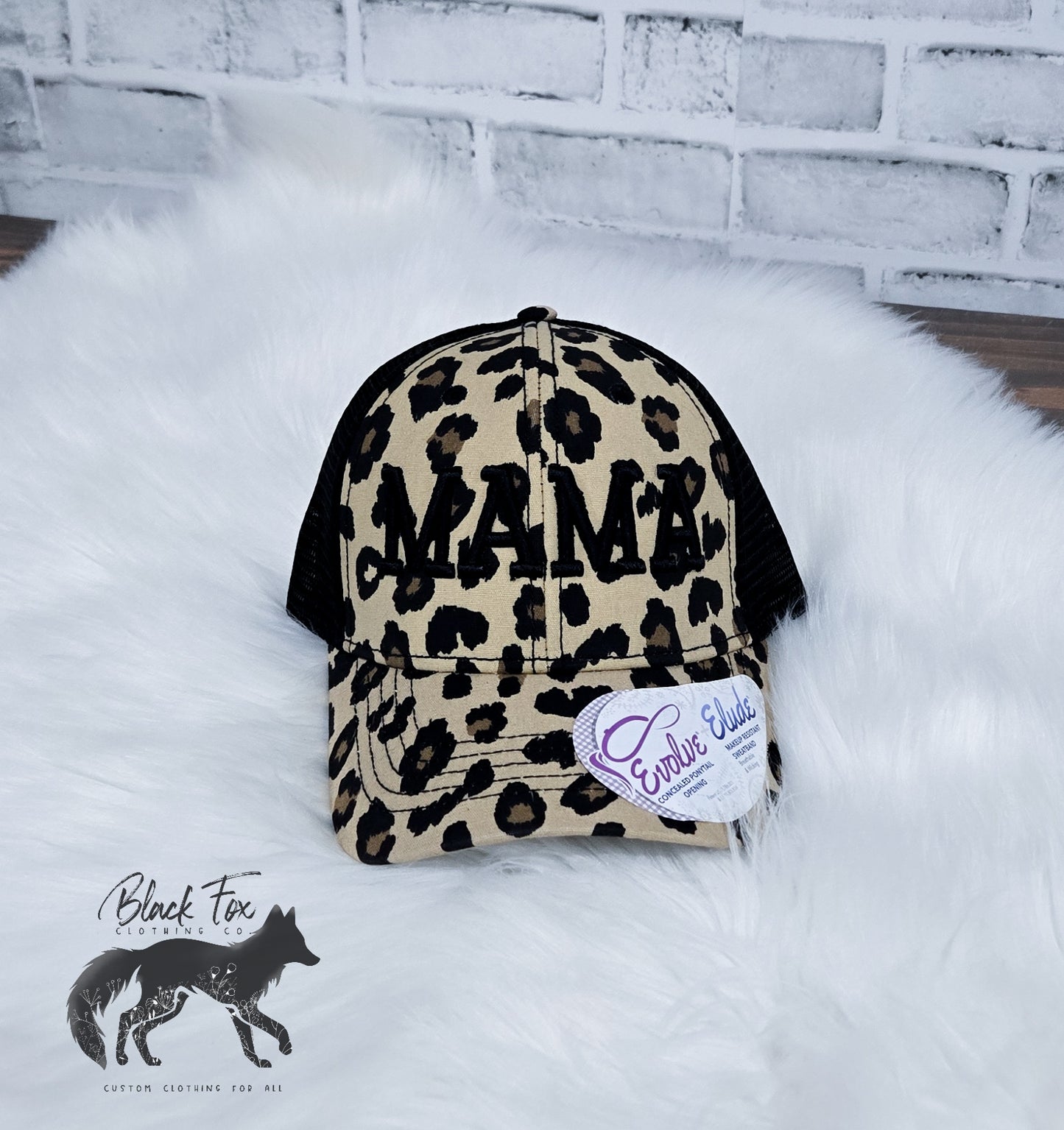 A brown leopard print trucker hat with 'MAMA' embroidered in capital letters on the front.
