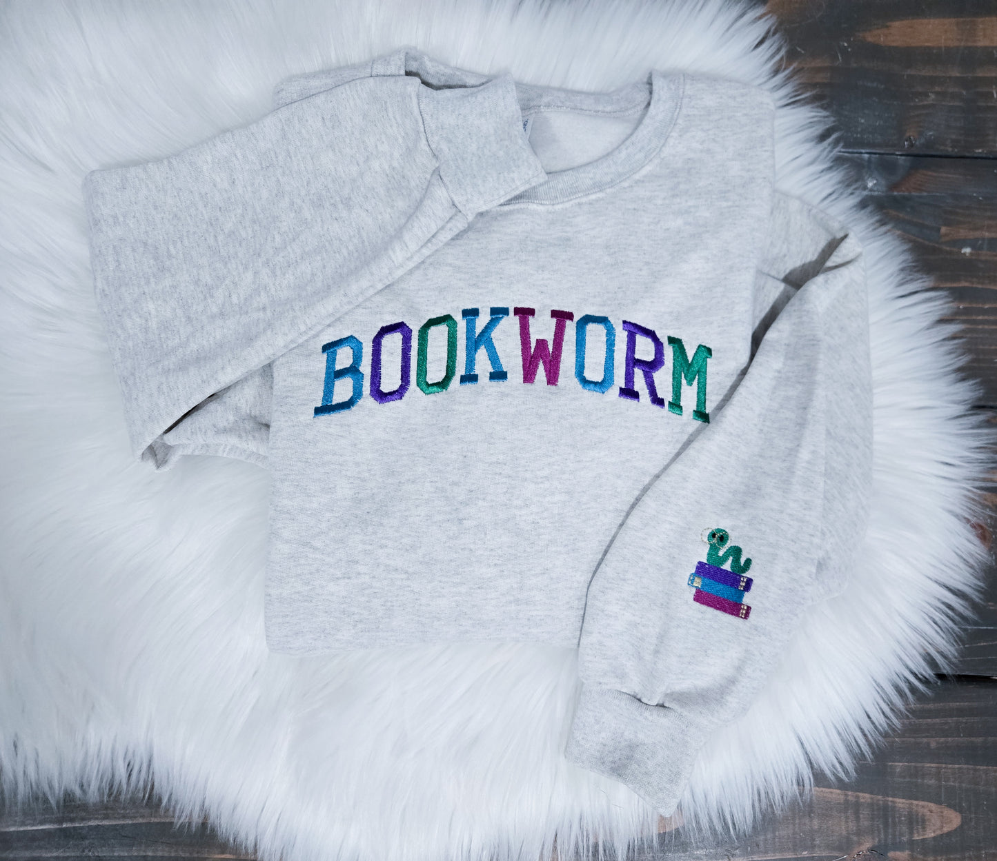 Gray sweatshirt with 'BOOKWORM' text on a fluffy white surface