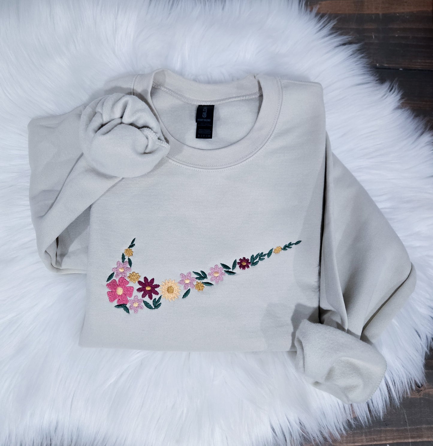 Light tan sweatshirt with floral design on a fluffy white surface