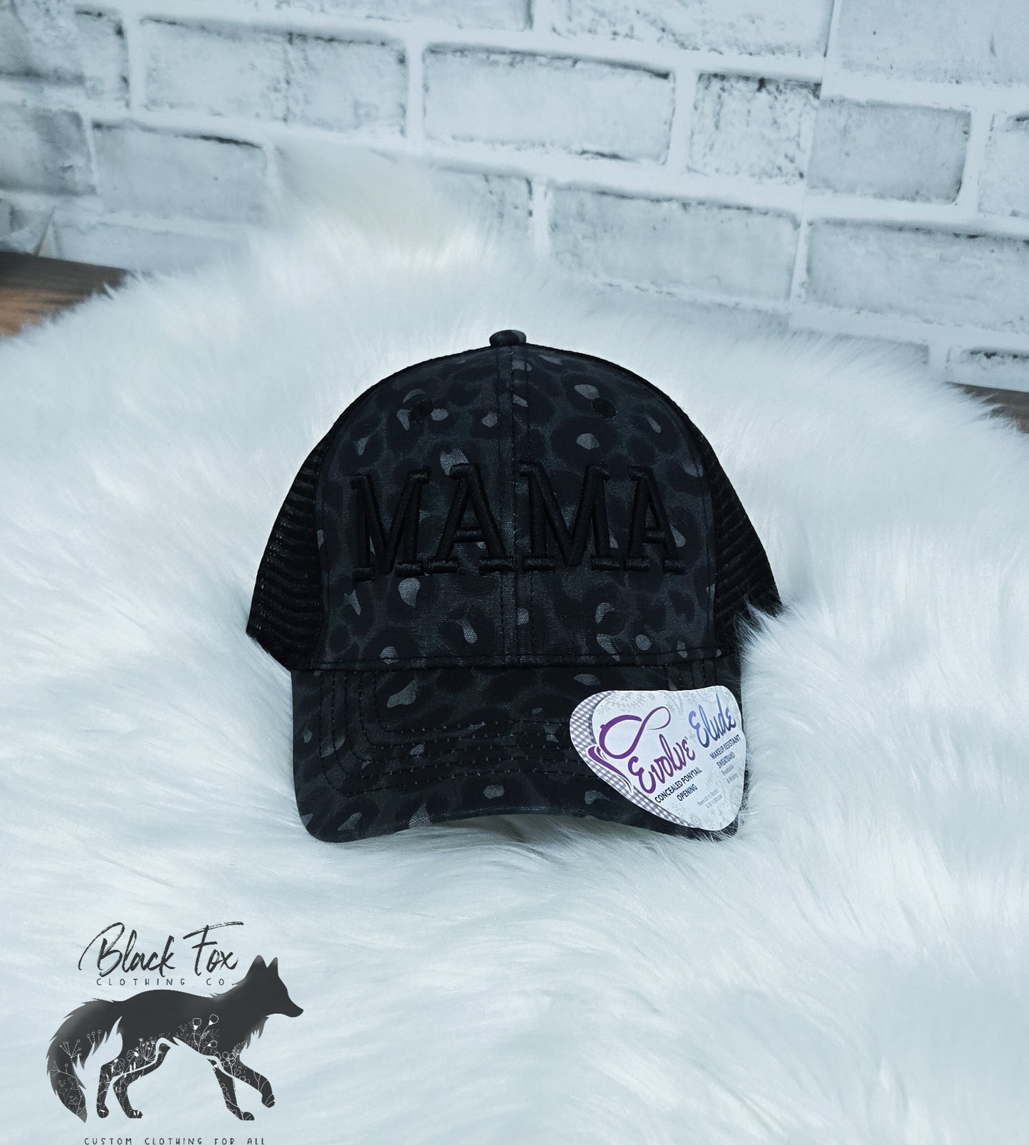 A black leopard print trucker hat with 'MAMA' embroidered in capital letters on the front.