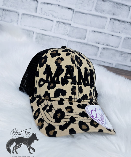 A brown leopard print trucker hat with 'MAMA' embroidered in capital letters on the front.