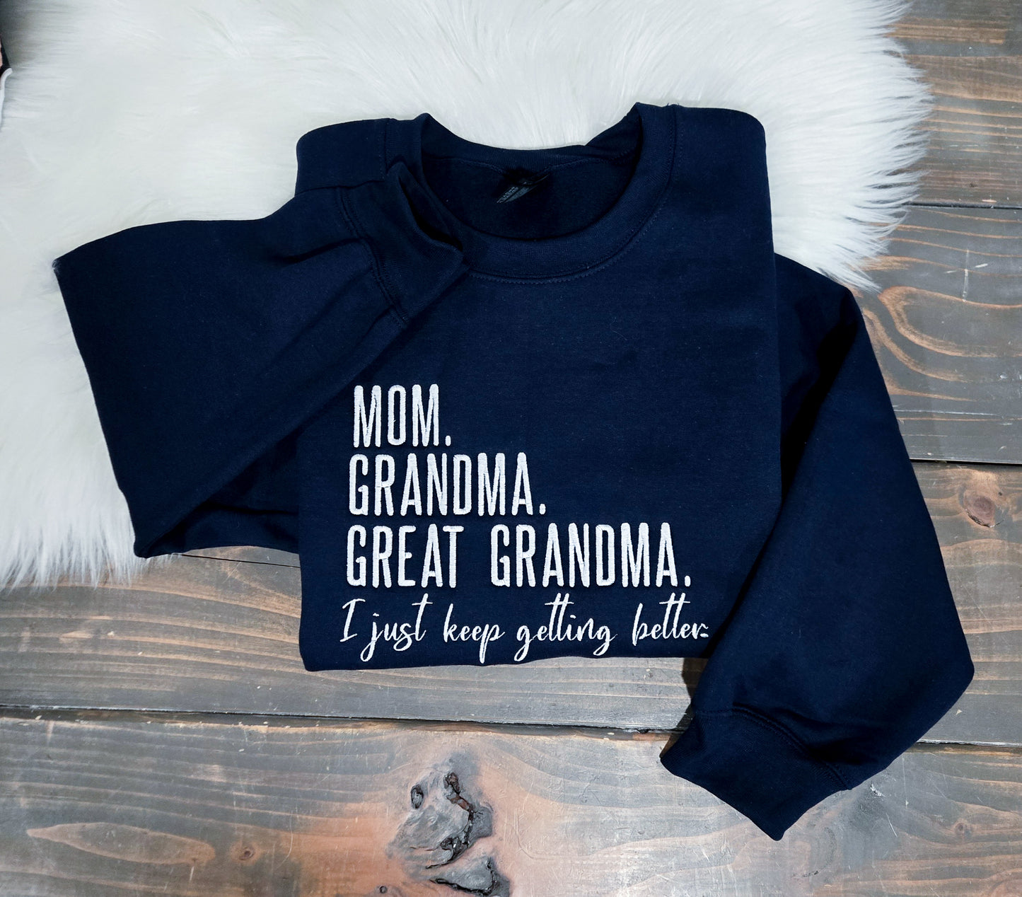 Navy blue sweatshirt with humorous text on a wooden surface