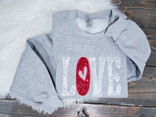 Gray sweatshirt with 'LOVE' print featuring a red heart on a wooden surface